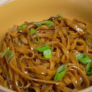 Noodles in a bowl with Garlic chili oil and sliced scallion.