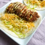 Crispy chicken on top of a flour tortilla with shredded lettuce and cheese. Honey mustard drizzle all over.