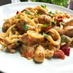 Fiesta chicken pasta on a white plate with bell peppers.