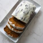 Pumpkin banana bread sliced with cream cheese glaze on a white plate.