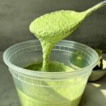 Green Cilantro lime sauce dripping from a spoon.