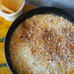 Elote dip inside a cast iron skillet with chips on the side.