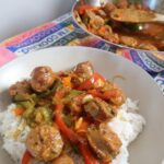 Italian sausage and peppers in a bowl on top of white rice.