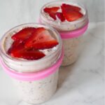 close up of strawberry overnight oats in a jar with sliced strawberries on top