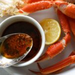 cajun butter sauce in a spoon next to crab legs