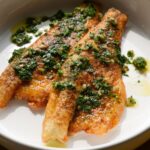 Pan Seared Branzino on a white plate with dill chimichurri on top.