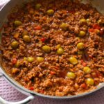 Easy picadillo with ground beef, olives, and tomato sauce served over rice and plantains.