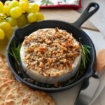Baked brie with honey topped with walnuts, and rosemary.