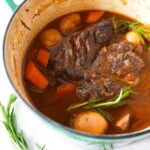 Dutch oven pot roast with carrots, potatoes, and rosemary served in a Dutch oven
