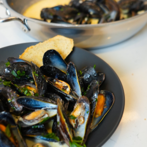 Mussels in white wine sauce garnished with fresh parsley and served with toasted bread for dipping.