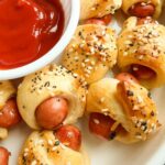 Pigs in a blanket made with mini hot dogs wrapped in flaky crescent rolls, sprinkled with everything bagel seasoning.