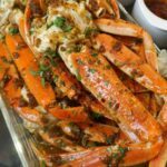 Garlic butter crab legs topped with parsley and lemon slices, ready for serving.