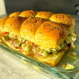Grinder sliders with melted cheese, deli meats, and crunchy grinder salad on Hawaiian rolls.
