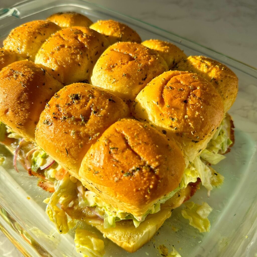 Grinder sliders with melted cheese, deli meats, and crunchy grinder salad on Hawaiian rolls.