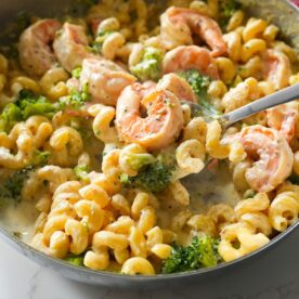 Shrimp Alfredo with broccoli in a skillet.