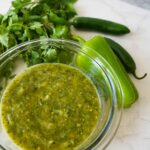 A bowl of homemade tomatillo salsa verde, garnished with fresh cilantro, ready to be served with chips or tacos.