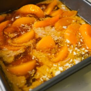 Peach cobbler ingredients in a pan before baking.