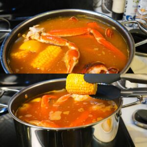 Crab legs, corn, and lobster in seafood boil pot with broth.