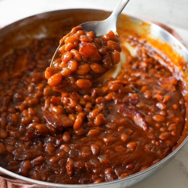 Baked beans with crispy bacon in a skillet, served warm and bubbly straight from the oven.