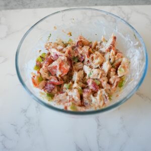 Lobster mixed with celery, mayo and herbs in a bowl.