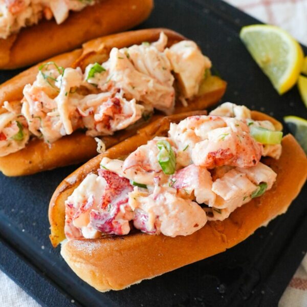 Lobster roll with creamy lobster salad in a toasted bun, garnished with herbs and lemon.