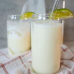 A glass of creamy Brazilian lemonade with ice and fresh lime slices.