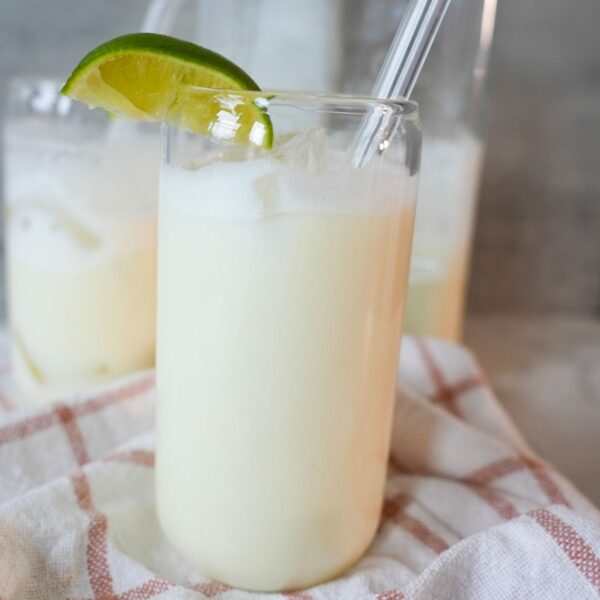 A glass of creamy Brazilian lemonade with ice and fresh lime slices.