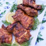 Lemon garlic chicken on a plate with dill and lemon garnish.