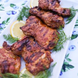 Lemon garlic chicken on a plate with dill and lemon garnish.