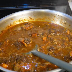 Jamaican oxtail stew in a pan on the stove.