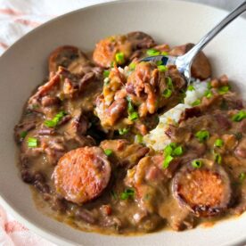 Red beans and white rice in a bowl with chopped chives on top.