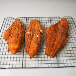 Fried catfish cooling on a wire rack.