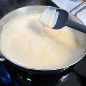Gravy in a pan dripping off a spatula.