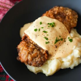 Golden chicken fried steak topped with creamy white gravy and chopped parsley, served with mashed potatoes.