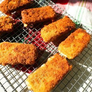 Golden mozzarella sticks on a wire rack.