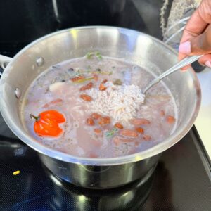Rice in a pot with scotch bonnet, peas, coconut milk and beans.