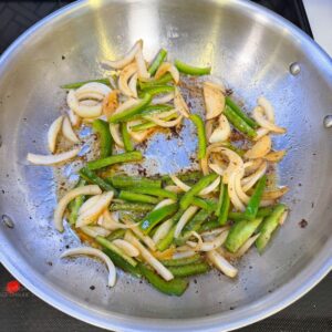 Onions and peppers cooking in a pan.