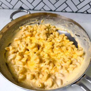 Macaroni in a pan with cheese sauce.
