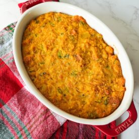 Golden brown cornbread dressing in a small baking dish with a soft center and crisp, buttery edges.