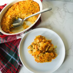 Golden brown cornbread dressing in a small baking dish with a soft center and crisp, buttery edges.
