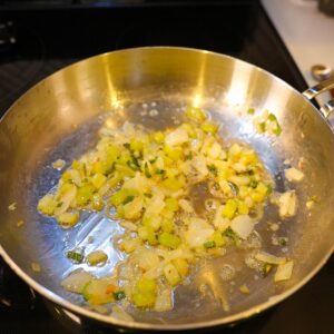 Onion, celery, sage and garlic cooking in a pan.