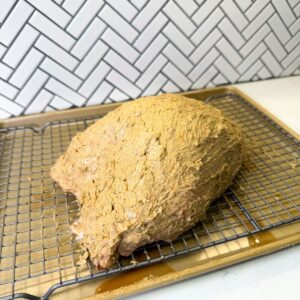 Turkey breast with jerk compound butter on a wire rack.