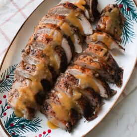 Roasted jerk turkey breast sliced on a plate with gravy.