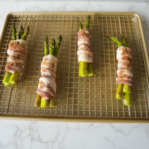 Bacon wrapped asparagus on a baking tray before baking.