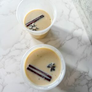 Cremas in containers with cinnamon sticks.