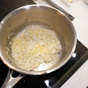 Onions sautéing in butter in a saucepan.