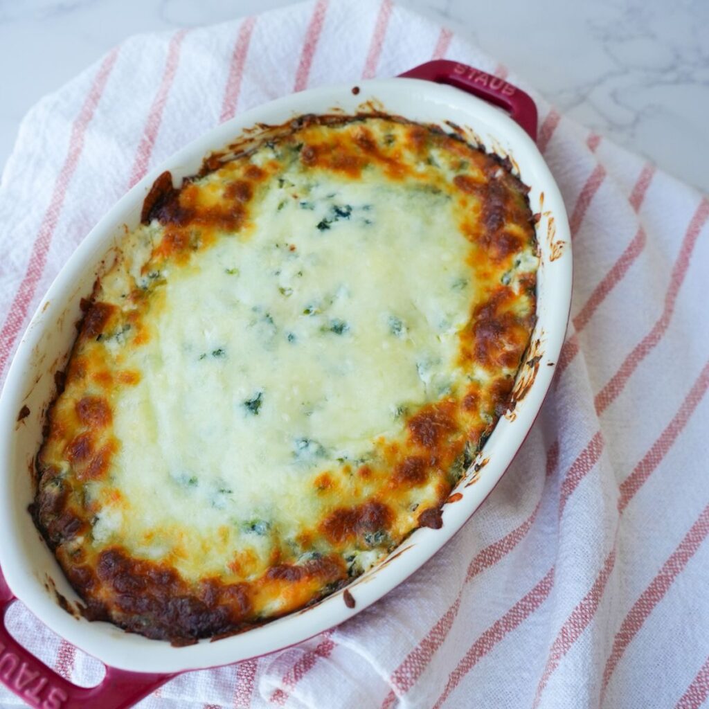 Cheesy spinach artichoke dip in a baking dish.