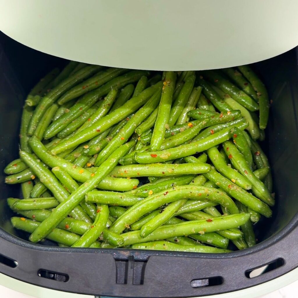 Green beans in an air fryer before cooking.