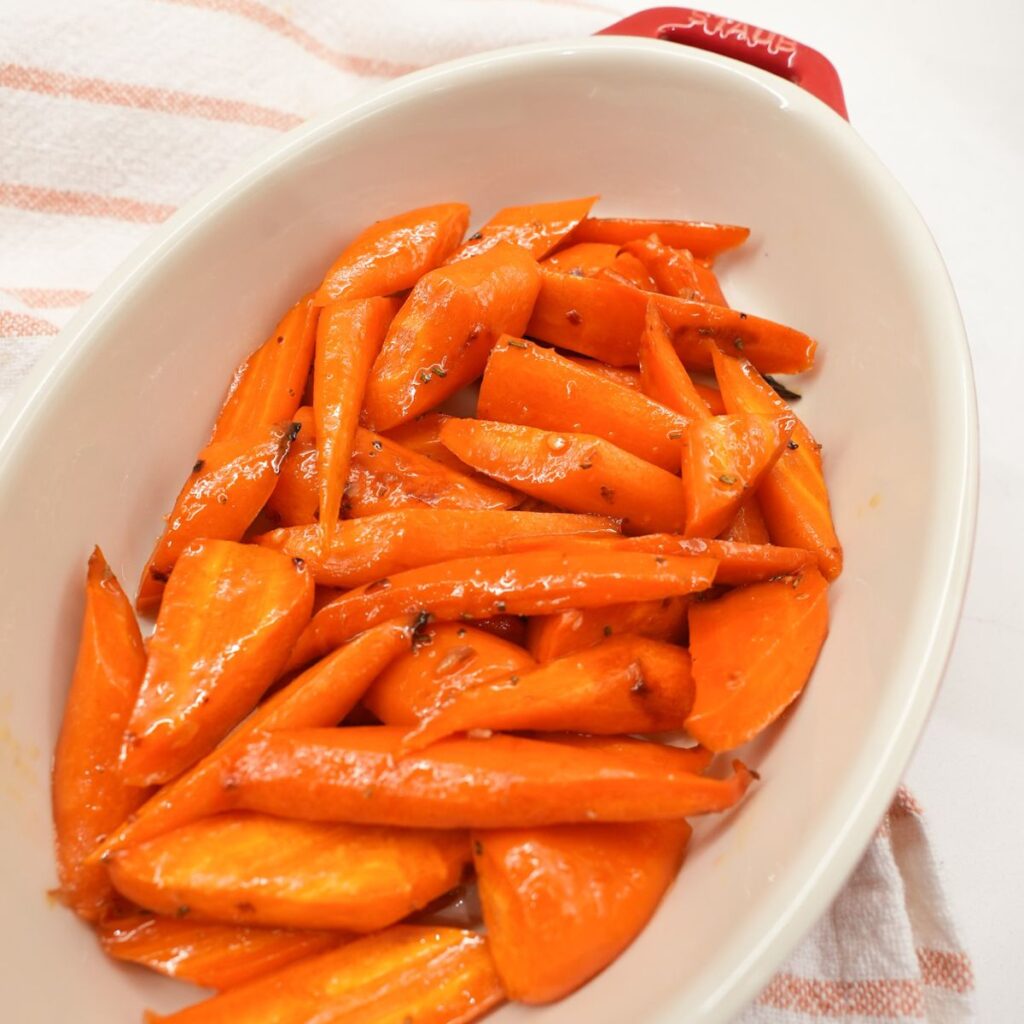 Roasted honey glazed carrots in a serving dish with rosemary and caramelized edges.