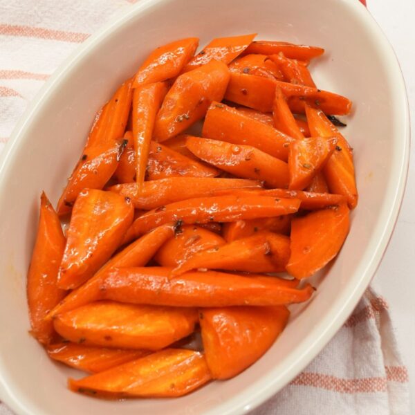 Roasted honey glazed carrots in a serving dish with rosemary and caramelized edges.